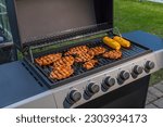 Small photo of Close-up view of cooking meat steak with corn on cob on gas grill in courtyard of villa. Sweden.