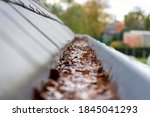 Small photo of A portrait of inside of a clogged roof gutter filled with water and autumn leaves. The water cannot run away, this is a typical chore in or after autumn when all leaves have fallen.