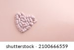 Heart made of pills on pink background. Creative concept for Valentine