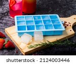 Blue silicone ice cube tray on table with fruit and strawberry drink