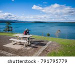 Small photo of May 30th 2015, man sitting on benching on a hill near a reservoir and watching birds on the water with his binoculars. Yan Yean Reservoir Park, VIC Australia.