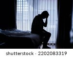 Small photo of Lonely man silhouette sitting on the bed feeling depressed and stressed in the dark bedroom, Depression and anxiety disorder concept