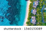 Tropical island bure accommodation in resort with reef and turquoise water and rocky outcrop Aerial shot from above. Fiji island Kokomo luxury resort. Palm trees overlooking Pacific Ocean in summer