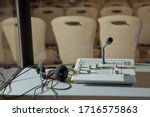 translators cubicle . interpreting - Microphone and switchboard in an simultaneous interpreter booth . Soft focus of wireless Conference microphones and notebook in a meeting room.