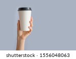 Mockup of woman hand holding up a Coffee paper cup isolated on grey background. Front view
