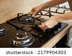 Small photo of Hands installing gas stove grill after cleaning, Kitchen appliance maintenance