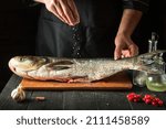 Small photo of The chef prepares fresh fish bighead carp sprinkling salt. Preparing to cook fish food. Working environment in the restaurant kitchen.