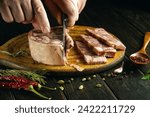 Small photo of Slicing meat brawn on a kitchen board with a knife in the chef hand for preparing a snack.