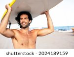 Young handsome man with his surfboard. Happy man relaxing at the beach
