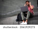  Handsome man working with laptop on city street. Man using his laptop while sitting on stairs outdoors.