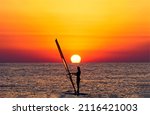 Windsurfing at sunset horizon view. Windsirfer girl at sunset. Sunset windsurfing. Windsurfing at sunset
