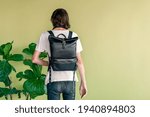 Small photo of Black Laptop backpack, Rucksack, tablet bag, leather, puristic design. Hipster in a white t-shirt, black jeans and a black leather backpack. Back view. Green background.