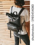 Small photo of Young guy with black leather backpack indoors. Back view. Black Laptop backpack, Rucksack, tablet bag, leather, puristic design.