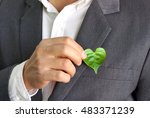 Businessman holding a green heart leaf / Business with corporate social responsibility and environmental concern                               