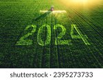 2024Happy New Year concept and Aerial view of farming tractor plowing and spraying on field.