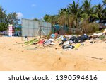 Small photo of Duong Dong, Phu Quoc island, Vietnam - March 19, 2019: garbage dump on a sandy beach beyond the fence of a beach restaurant. Trash left by people on the coastline. Boorish attitude to nature