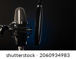 Small photo of Professional microphone with a pop filter on a black and blue background. Macro photography. Recording studio, singing, instrumental music, spoken word.