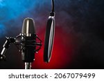 Small photo of Professional studio microphone with pop filter on red-blue smoke background. Nightclub, singing, spoken word, television, radio, recording studio, instrumental music.