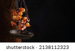 Small photo of A professional chef prepares assorted seafood - octopus, shrimp and pieces of red fish. Seafood in frozen flight on a black background. Sea food. Healthy food, vegetarian food.