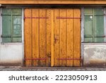 Closed, wooden double door or hinged door in an old, dilapidated building