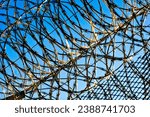 Small photo of Barbed wire or barbed wire on a prison fence in oblique view against a blue sky