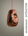 Small photo of Modern streamlined mirror copper chandelier. Metal shaped pendant lamp interesting form isolated on grey background. Loft style.