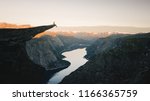 Man traveler on Trolltunga rocky cliff edge in Norway mountains Travel Lifestyle adventure emotional concept extreme vacations outdoor sunrise, tourist sitting alone