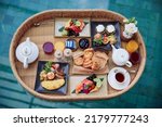 Floating breakfast tray in luxury pool hotel. Healthy set of dishes served in tropical resort. Relaxing, Exotic summer travel, holiday, vacation and weekend. Top view