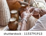 Small photo of man makes a basketwork with finished basketwork in background
