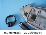 Textile urban backpack with laptop, external SSD, smartphone, headphones and thermos. Traveling with gadgets. Pre-flight screening. Hand luggage in airport. Carry liquid on board aircraft. Close-up