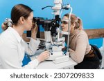 Small photo of Ophthalmologist with slit lamp examines eyes and cornea of woman. Ophthalmologist illuminates eye of patient with light from slit lamp to diagnose the eyes and cornea