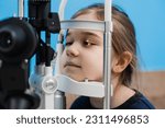 Small photo of Pediatric ophthalmologist with slit lamp examines eyes and cornea of child. Ophthalmologist illuminates eye of child with light from slit lamp to diagnose the eyes and cornea