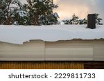 Small photo of Thick layer of snow hanging off the edge of the roof.