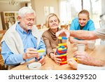 Small photo of Nursing care takes care of demented senior citizens while playing with colorful building blocks