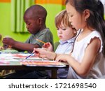 Different children concentrate together painting pictures in kindergarten