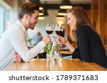 Small photo of Amorous young couple having a rendezvous at the restaurant drinking a glass of red wine