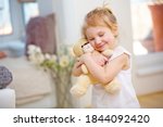 Small photo of Child cuddles with her soft cuddly toy at home