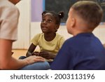 Small photo of African girl talks to daycare worker or childminder in international kindergarten