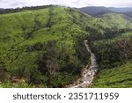 Small photo of Verdant mountain slopes meet the flowing embrace of a rocky river, a tableau of serene beauty where land and water coalesce in harmonious tranquility.