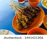 Small photo of Beeg and chicken satay on the orange plate