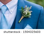 boutonniere made with lavender, rosemary, and babys breath tied with twine pinned to a blue jacket, blue tie, wedding day clothes
