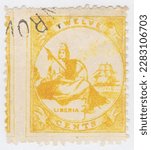 Small photo of LIBERIA - 1880: An 12 cents yellow postage stamp depicting a sitting Liberty with a sailing vessel in the background. Republic of Liberia, is a country on the West African coast