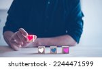 Small photo of the concept of love anything is love valentine day love yourself love anyone and your job, man picking wooden block with heart icon.