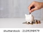 Hand putting a coin on pig saving. a pile of coins, business, investment, finance, and Money Saving for future concepts, save money.