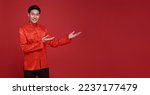 Small photo of Happy Chinese new year. Asian man presenting or showing open hand palm with copy space introduce for product isolated on red background.