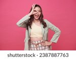 Small photo of Portrait happy Asian teen woman shows ok hand sign and looking at the camera on pink background.