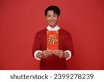 Happy Chinese new year. Asian man holding angpao or red packet monetary gift isolated on red background. Chinese text means great luck great happy.