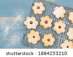 Flower shaped shortbread cookies filled with raspberry jam close up on blue wooden background