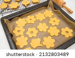 Sugar cookies in cute flower shapes close up on baking sheet. Step by step baking process