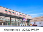 Small photo of Samut Sakhon, Thailand - March 31, 2023 : Large 7-11 Convenience Building Store with customer service parking lot area against blue sky background, low angle and perspective side view